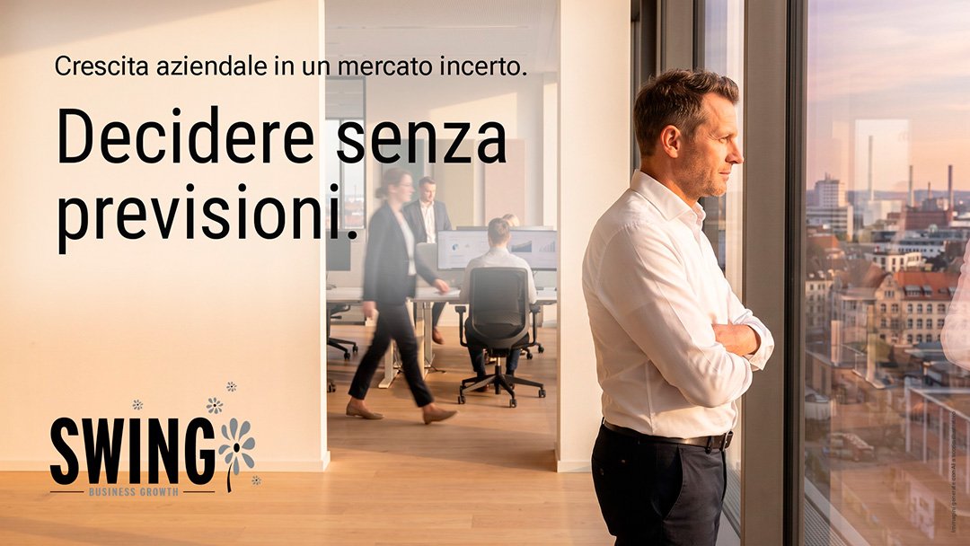 crescita aziendale in un mercato incerto Crescita aziendale in un mercato incerto: come si decide senza previsioni. Un dirigente osserva la città dalla vetrata di un ufficio direzionale, mentre il lavoro prosegue alle sue spalle.